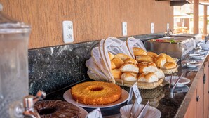 A buffet with various baked goods, including a bundt cake and a chocolate cake, on a marble countertop.