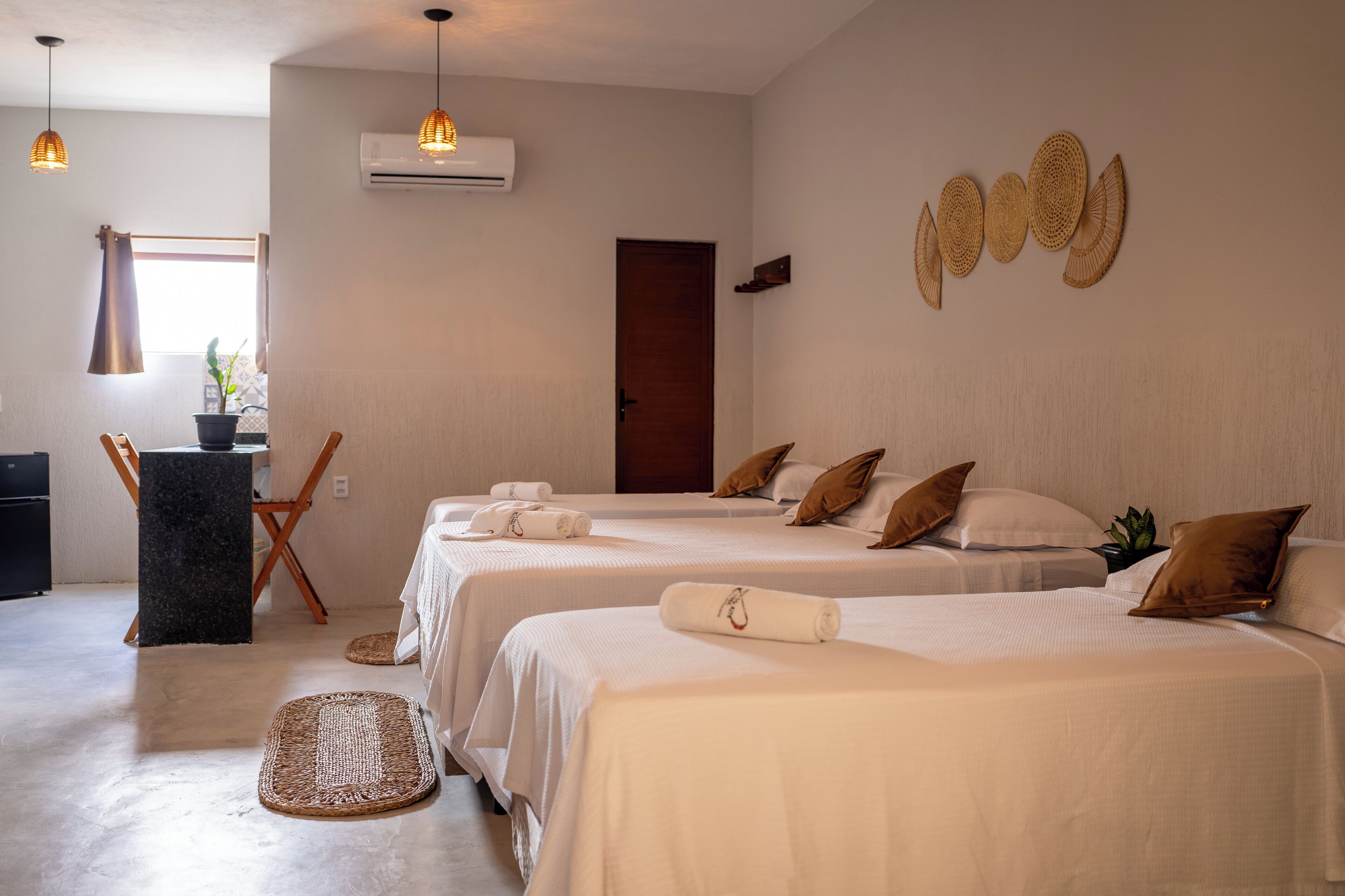 Una camera d'albergo con due letti, una piccola scrivania e una finestra con tende.