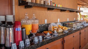 Un bufé de desayuno con diferentes alimentos, cafeteras y recipientes para condimentos.
