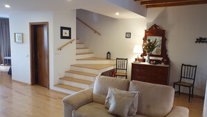 Ein Wohnzimmer mit einem beigefarbenen Sofa, einer Holztreppe und einer Holzbalkendecke.
