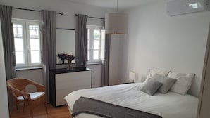 Ein Schlafzimmer mit einem Bett, einem Schminktisch, einem Stuhl und einem Fenster mit Vorhängen.