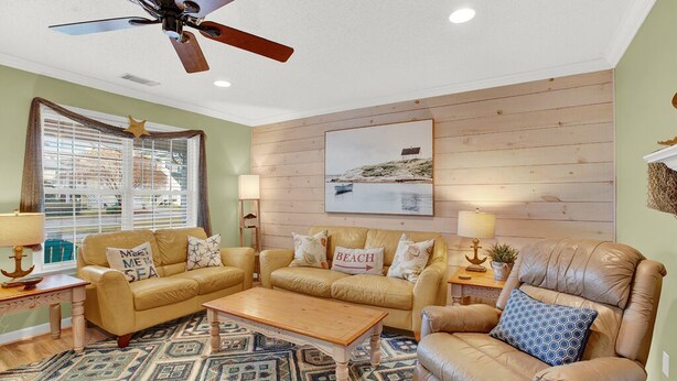 A cozy living room with a beige leather sofa, a matching armchair, and a patterned rug.