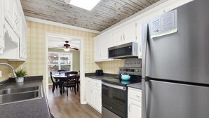 A modern kitchen with white cabinets, stainless steel appliances, and a dining area with a table and chairs.
