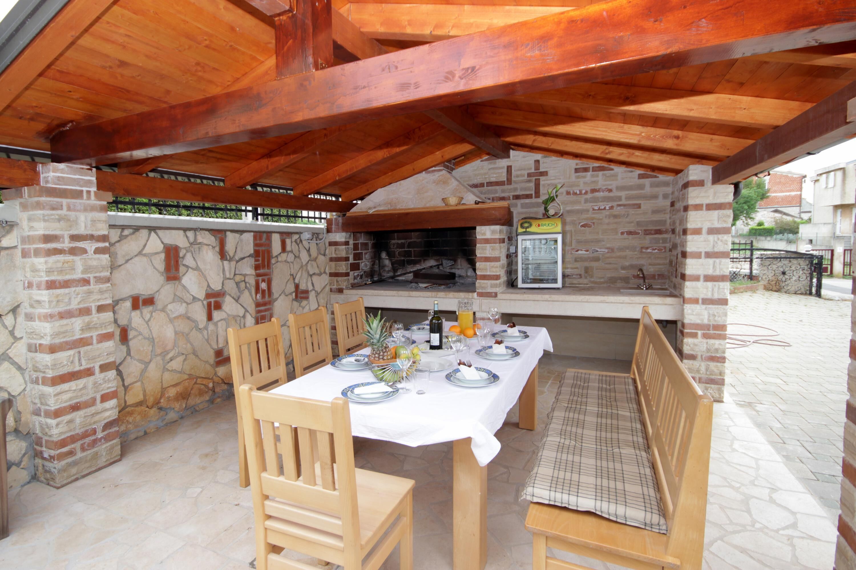 An outdoor patio with a brick fireplace, wooden table, and chairs.
