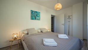 A neatly made bed with a quilted blanket, a bedside lamp, and a folded towel on the bed. - Apartments Domic (Medulin)