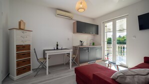 A compact living space with a kitchenette, a dining area, and a red sofa. - Apartments Domic (Medulin)