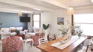 A living room with a sofa set, a dining table, and a TV mounted on the wall. - MAISIES ROBE - WI-FI - DOG FRIENDLY (Robe)