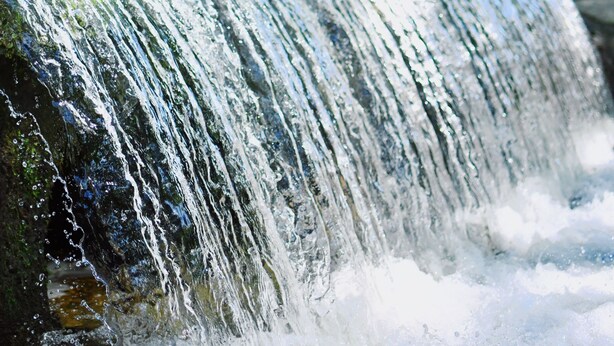 A waterfall in a park with trees and picnic tables in the background. - Sons Rio Cibolo Safari Cabin 1 (Marion)