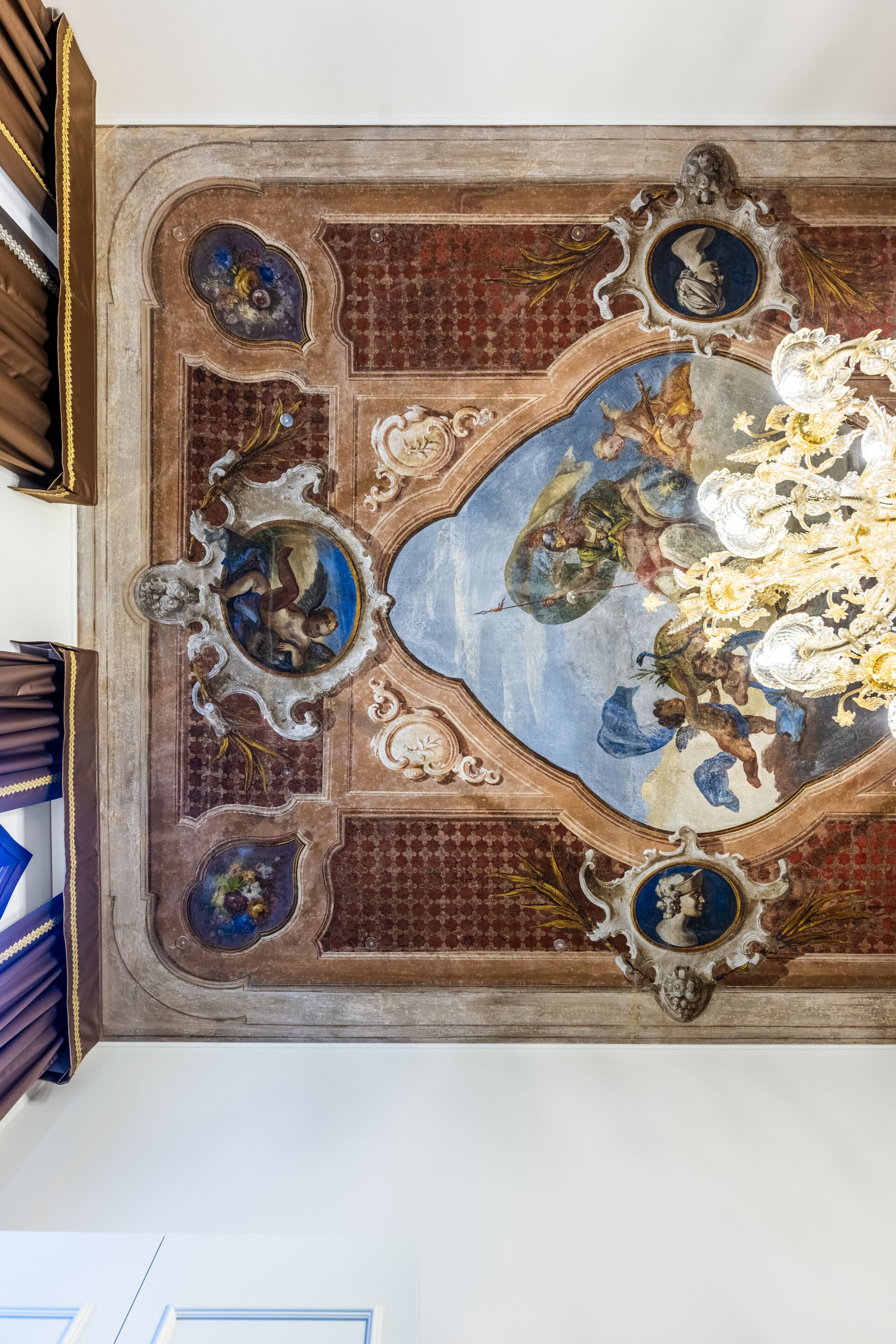 A detailed ceiling with ornate frescoes and classical architectural elements.