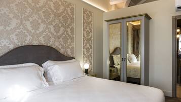 A neatly made bed with white linens, a headboard, and a nightstand with a lamp.