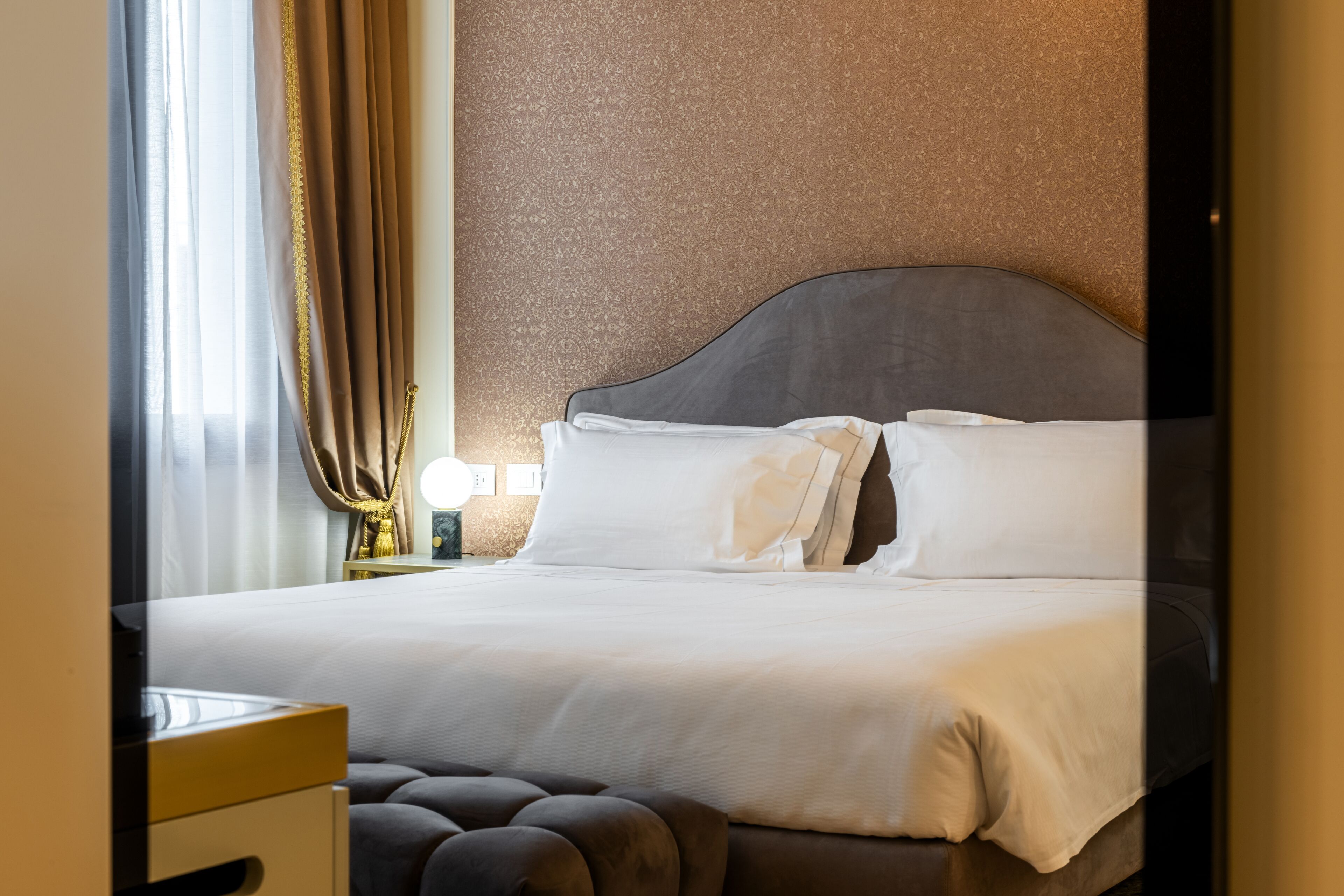 A neatly made bed with white linens and a dark headboard in a hotel room.