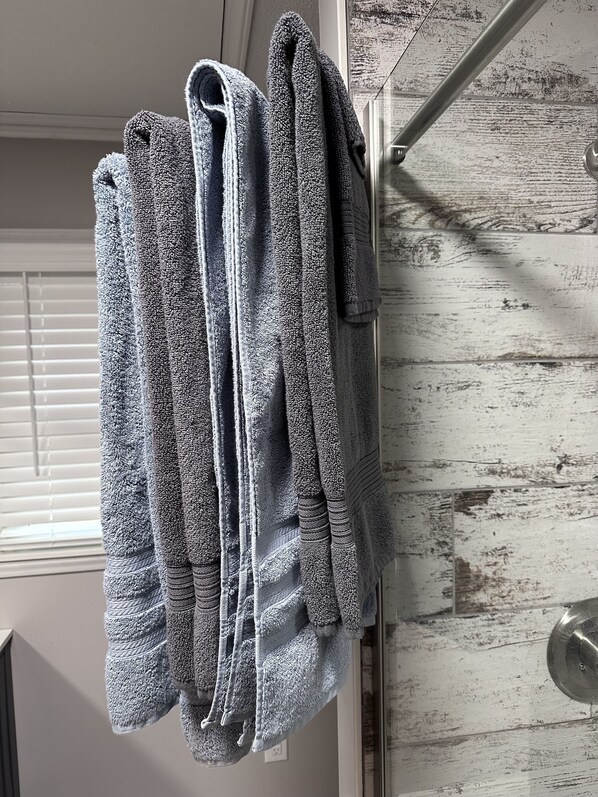 A bathroom with a wooden door and a towel rack holding several folded towels. - Charming farmhouse nestled within the breathtaking Uwharrie National Forest! (Troy)
