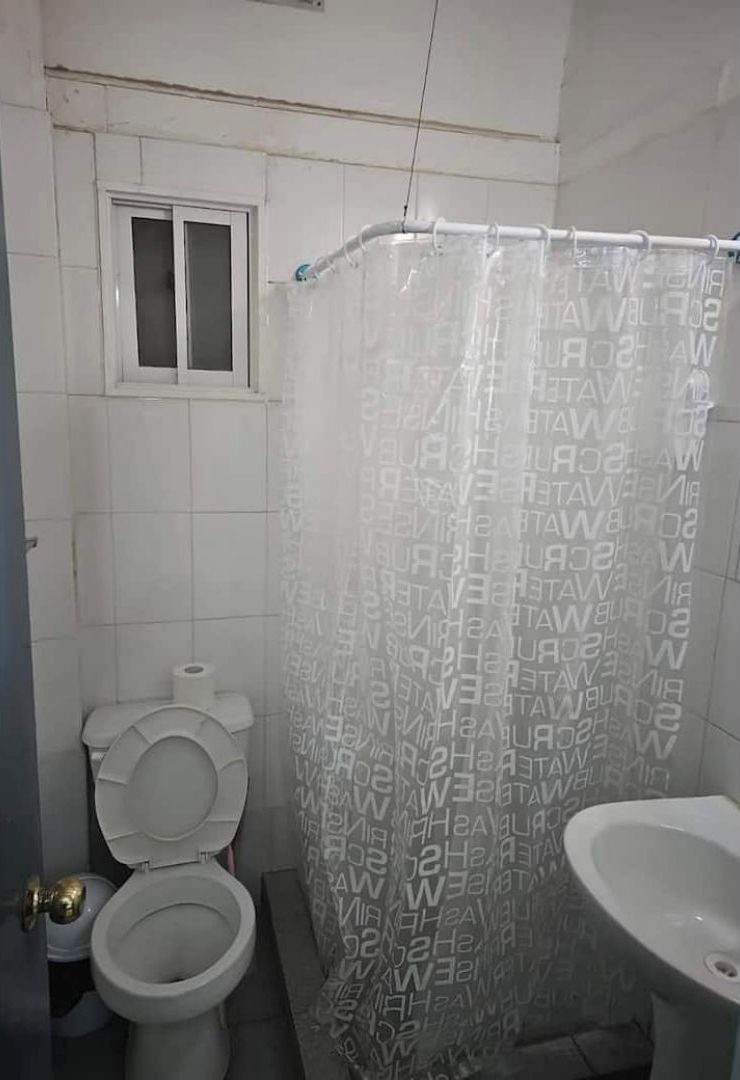A bathroom with a toilet, bidet, and a shower curtain with a repeating pattern.