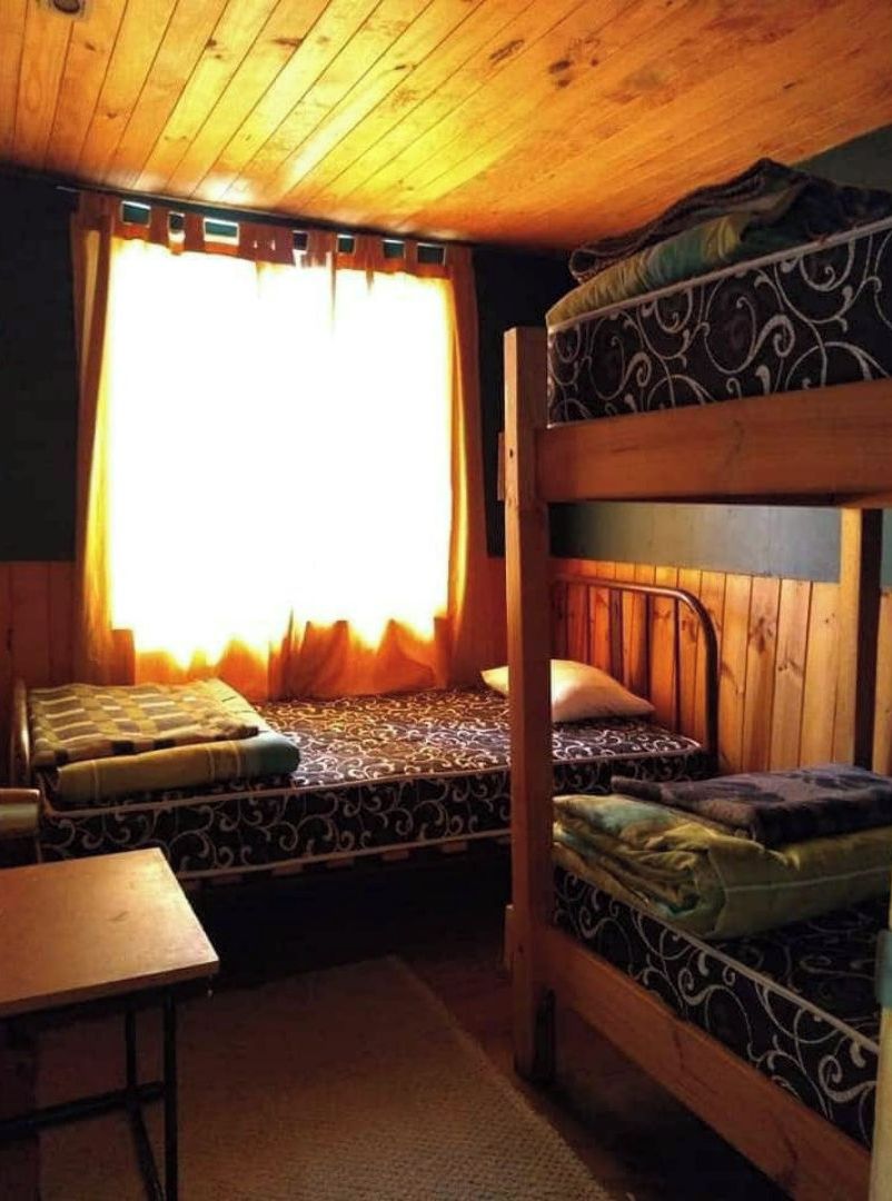 A cabin with two bunk beds, a small table, and a window with curtains.
