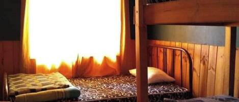 A cabin with two bunk beds, a small table, and a window with curtains.