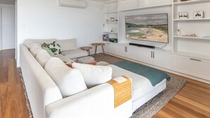 Ein modernes Wohnzimmer mit einer Couch, einem Fernseher und Regalen mit Dekorationselementen.