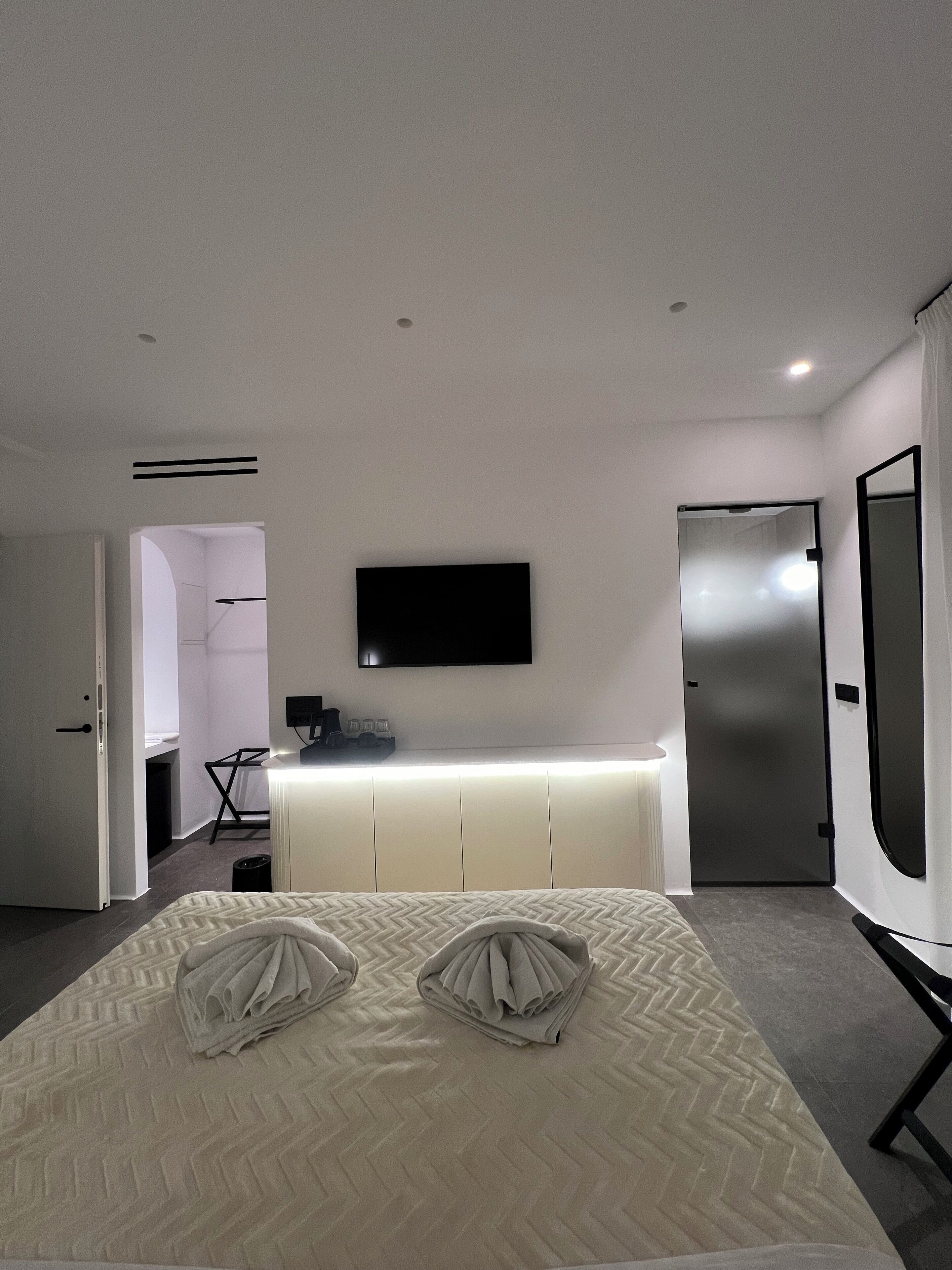 Ein modernes Hotelzimmer mit Bett, Schreibtisch, Flachbildfernseher und einer Tür.