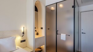 A modern hotel room with a bed, a wardrobe, and a bathroom. - Yalos hotel sunset view  (Mykonos)