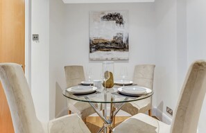 Un coin repas avec une table en verre, des assiettes blanches et des chaises de couleur beige.