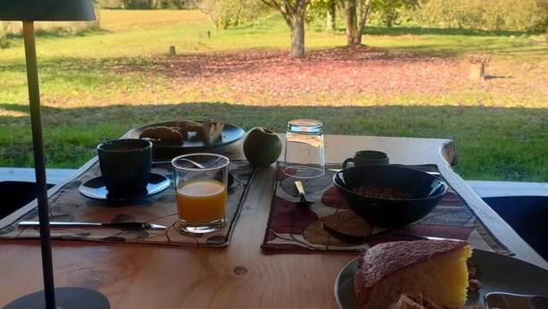 Preparación para el desayuno con una mesa, una lámpara y vistas a un árbol y al paisaje.