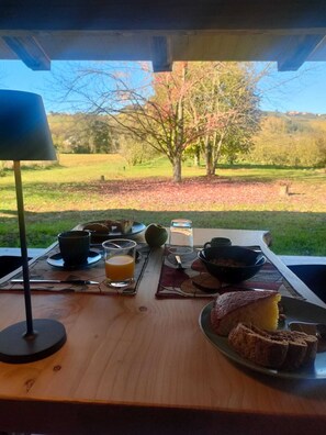 Frühstücksecke mit Tisch, Lampe und Blick auf Baum und Landschaft.