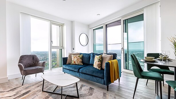 A modern living room with a sofa, armchair, coffee table, and dining area with chairs and a table.