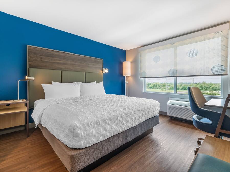 Quarto de hotel moderno com uma cama grande, uma escrivaninha e uma cadeira.