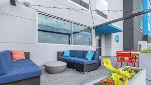 An outdoor seating area with two sofas, a round table, and a planter with flowers.