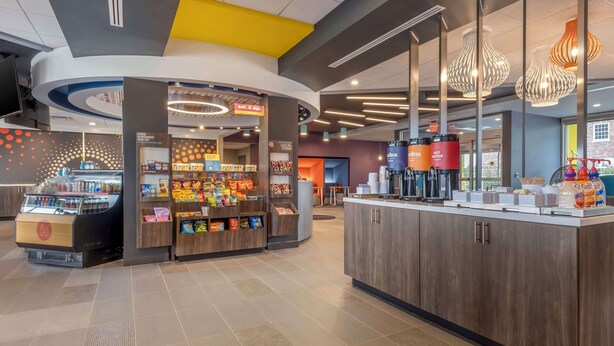 A modern food court with a variety of food stalls, a coffee station, and a seating area with a view of the outside.