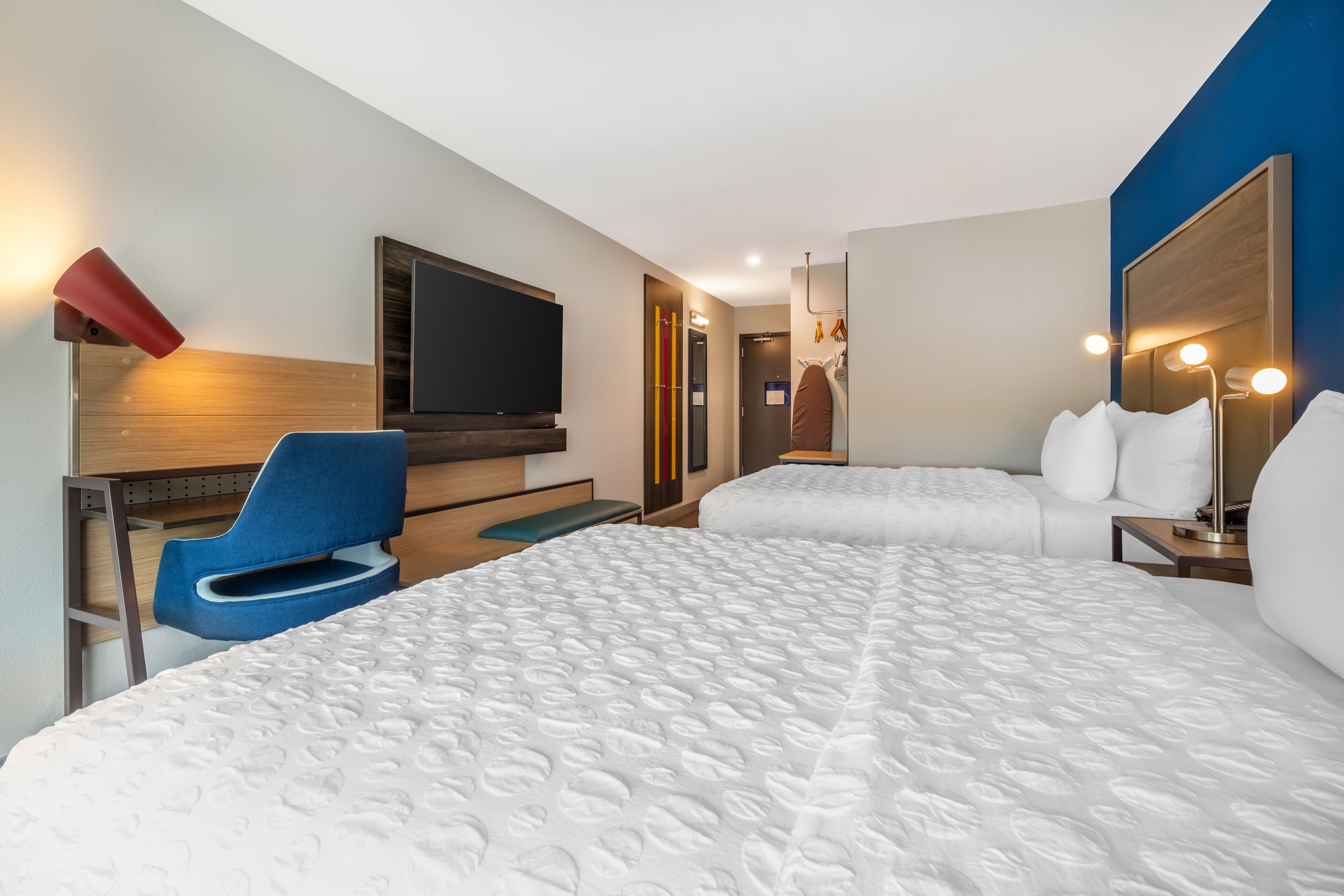 Hotellihuone, jossa on kaksi sänkyä, televisio, työpöytä ja tuoli.