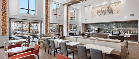 Un restaurante espacioso con techos altos, ventanas amplias y una cocina moderna.