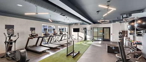 A modern gym with treadmills, elliptical machines, and weight equipment.