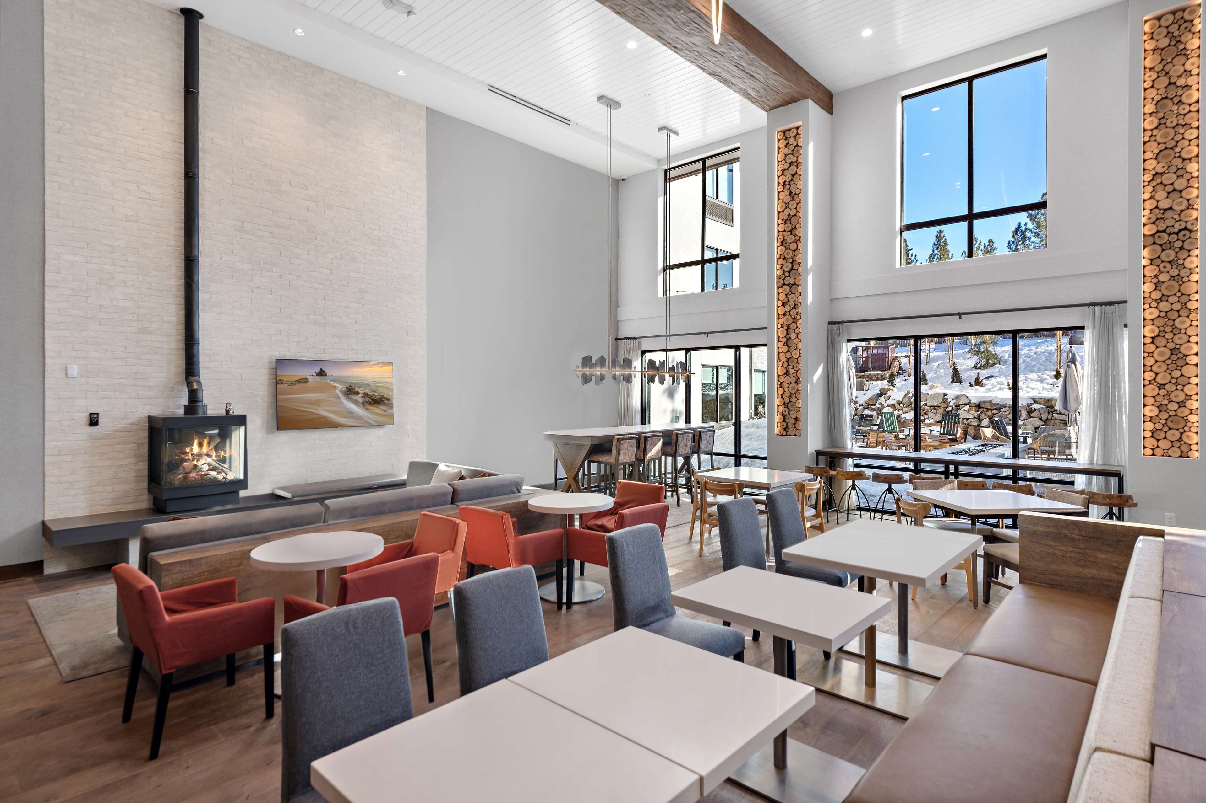 A spacious indoor area with high ceilings, large windows, and a fireplace.