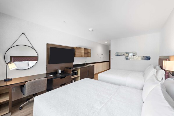 A modern hotel room with a bed, a desk, a chair, a TV, a mirror, and a small kitchenette. - Hampton Inn Big Bear Lake (Big Bear Lake)
