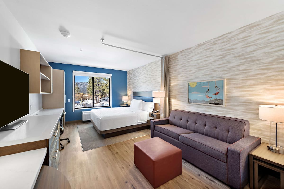 Ein modernes Hotelzimmer mit einem Bett, einer Couch, einem Schreibtisch und einem Fernseher.