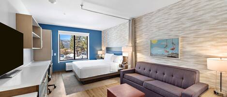 Una habitación de hotel moderna con una cama, un sofá, un escritorio y un televisor.