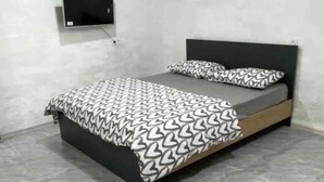 A bedroom with a bed, a TV mounted on the wall, and a patterned bedspread. - Modern, brand new rental unit,
Lovelv studio (Yerevan)