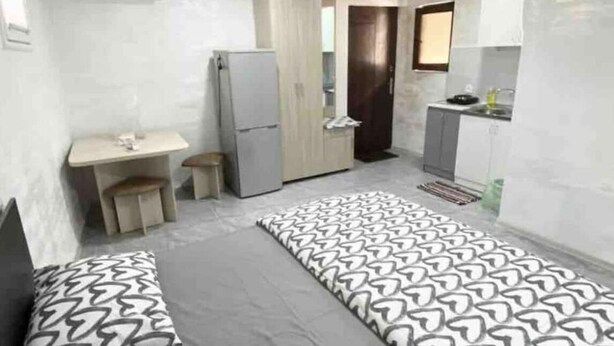 A compact room with a bed, a desk, a small kitchenette, and a door leading to another room. - Modern, brand new rental unit,
Lovelv studio (Yerevan)