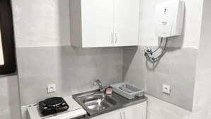 A small kitchenette with white cabinets, a sink, a dish rack, and a trash can. - Modern, brand new rental unit,
Lovelv studio (Yerevan)