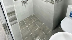 A small, tiled bathroom with a shower, a toilet, and a glass door. - Modern, brand new rental unit,
Lovelv studio (Yerevan)