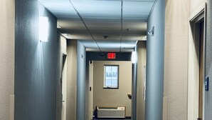 A hallway with carpeted floors, beige walls, and doors on both sides. - Garner Inn & Suites (Garner)