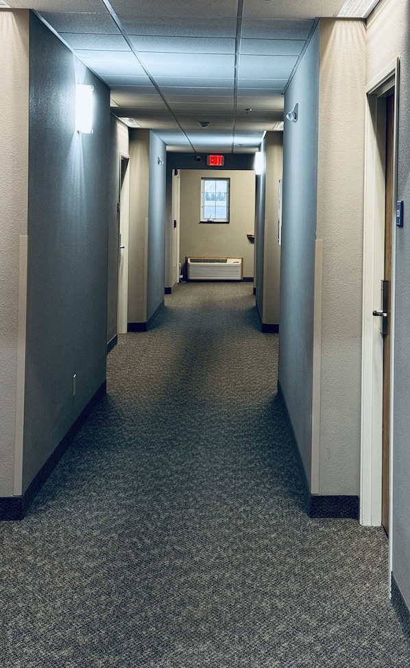 A hallway with carpeted floors, beige walls, and doors on both sides.