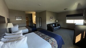A hotel room with two beds, a sofa, a desk, and a window. - Garner Inn & Suites (Garner)