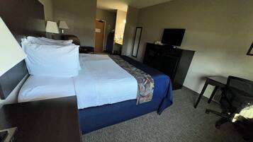 A hotel room with a bed, a desk, a chair, a television, and a wardrobe.