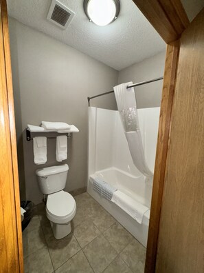 Une petite salle de bain comprenant des toilettes, une douche avec une porte en verre et un porte-serviettes.
