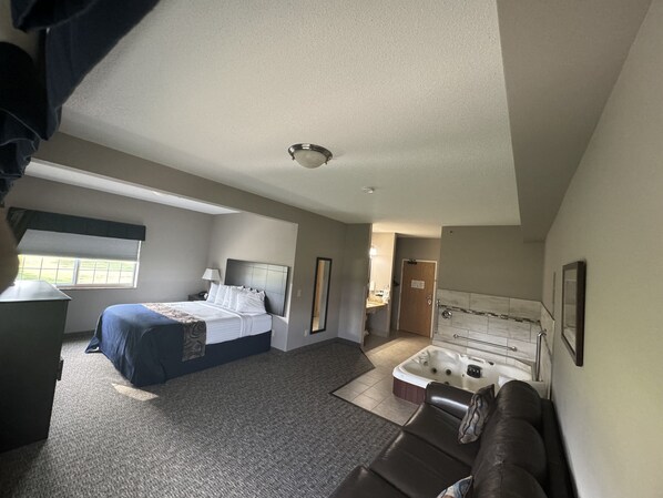 Une chambre d’hôtel comprenant un lit, un bureau, un canapé, un jacuzzi et une salle de bain.