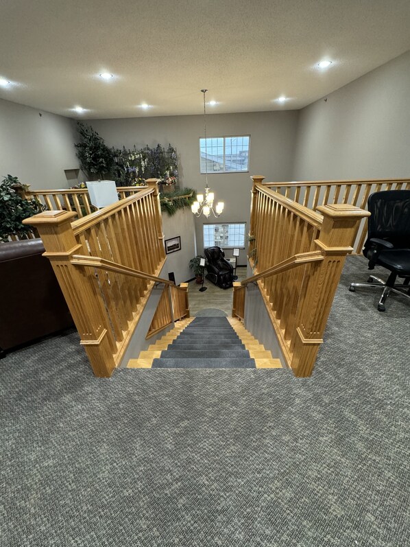 A staircase with wooden railings leading to a lower level. - Garner Inn & Suites (Garner)