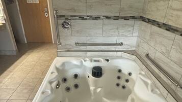 Un bagno con una vasca da bagno ampia, una zona doccia e una porta con un cartello.