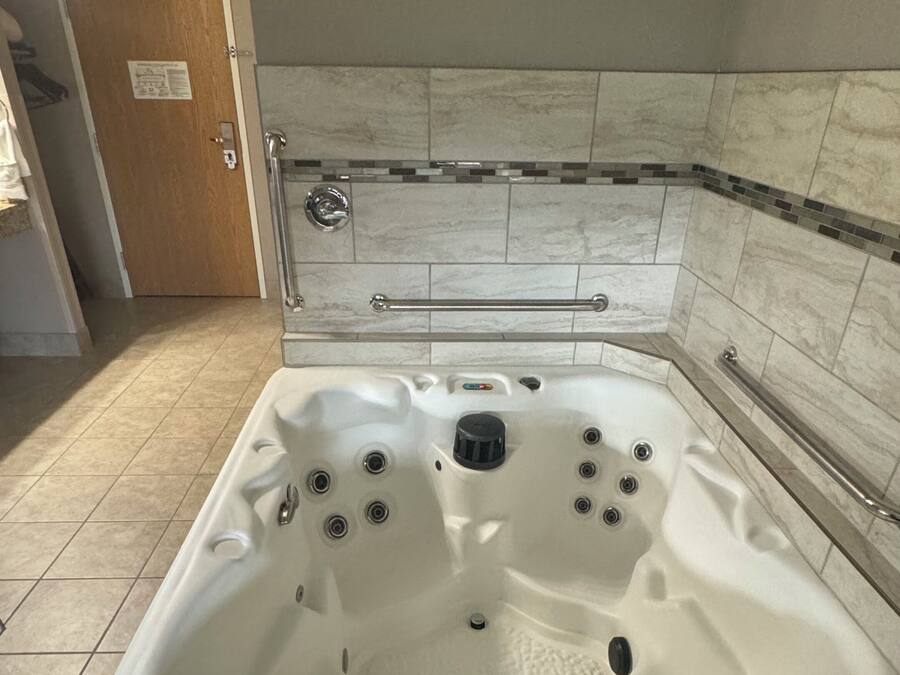 Un bagno con una vasca da bagno ampia, una zona doccia e una porta con un cartello.