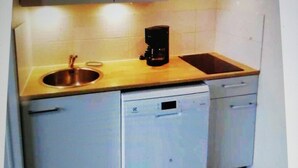 Una cocina compacta con un lavabo, una cafetera y un lavavajillas.